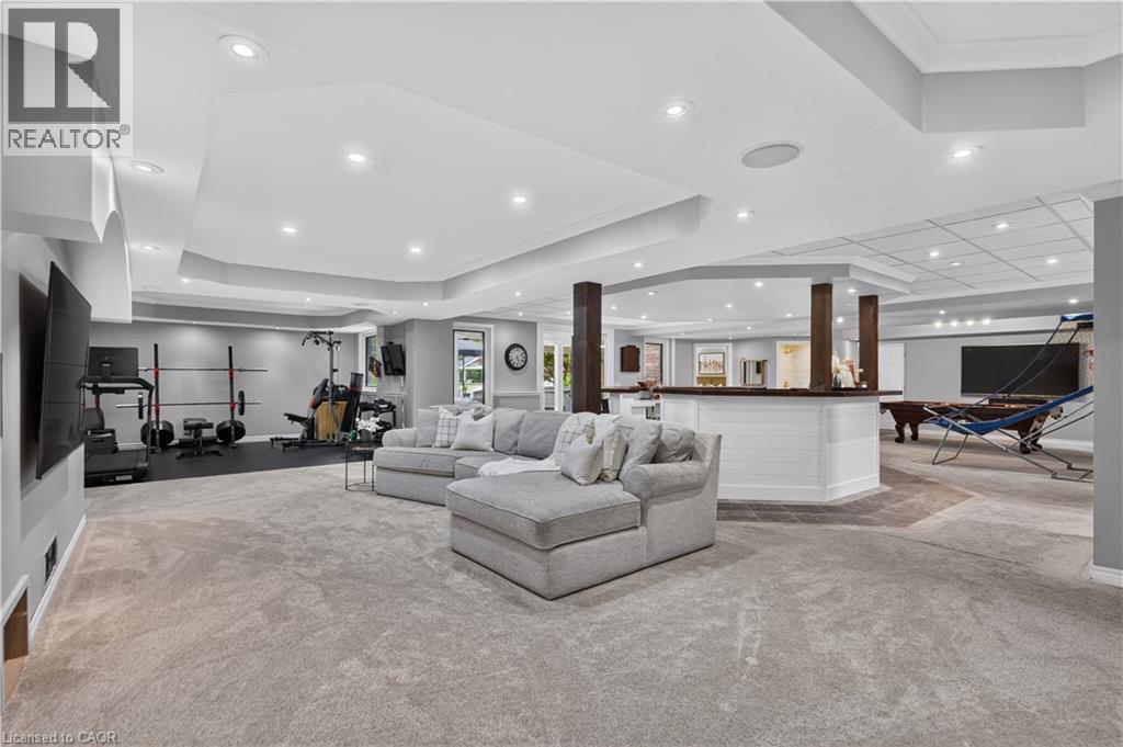 Spacious lower-level entertainment area featuring recessed lighting, tray ceilings, and varied flooring - 2050 15 Side Road, Milton, ON - Indoor