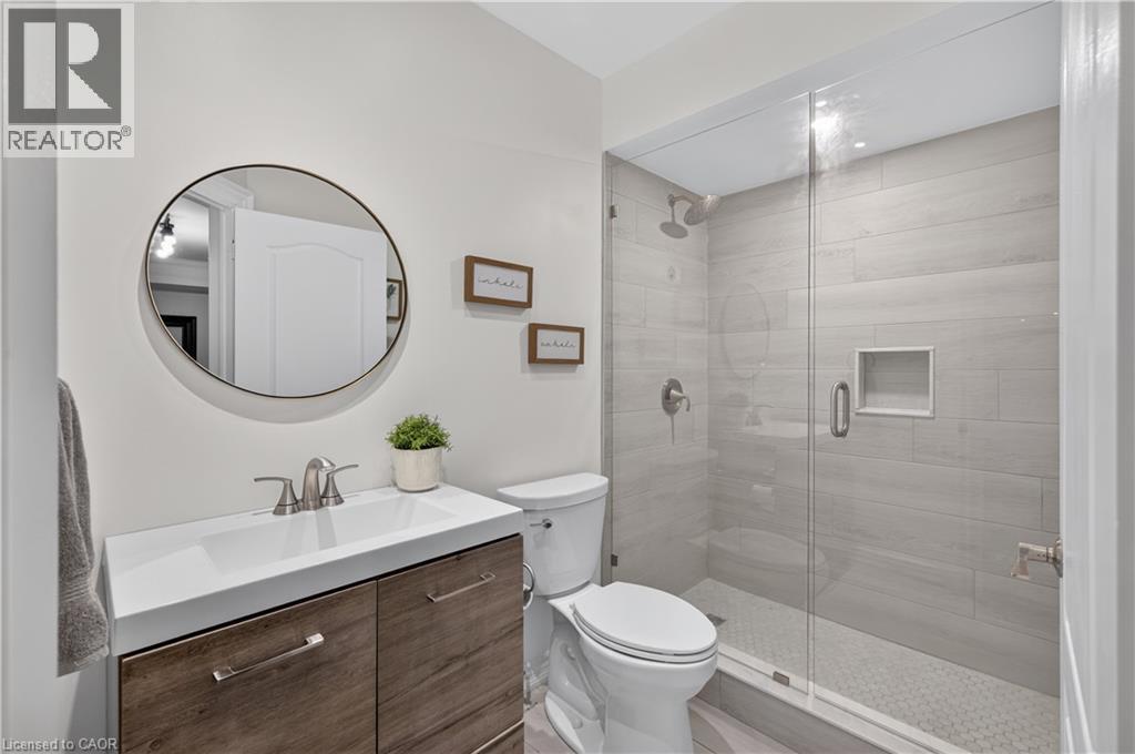 Bathroom with a frameless glass shower enclosure featuring large-format rectangular wall tiles and a hexagonal floor tile - 2050 15 Side Road, Milton, ON - Indoor Photo Showing Bathroom