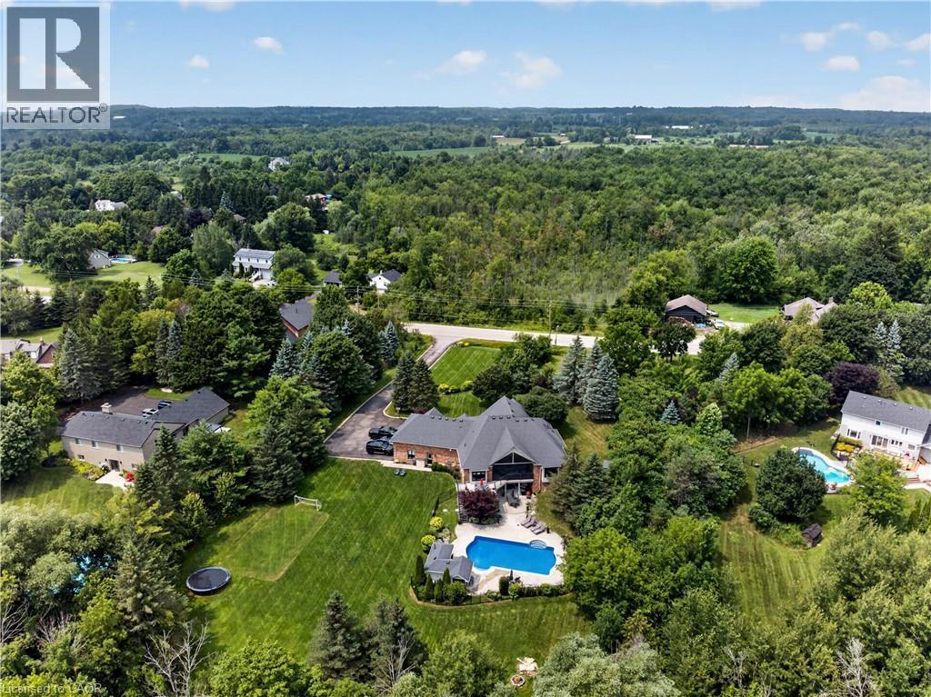 Expansive property featuring a brick exterior residence with a multi-level roofline, an in-ground swimming pool, and a large grassy yard with mature trees - 2050 15 Side Road, Milton, ON - Outdoor With View