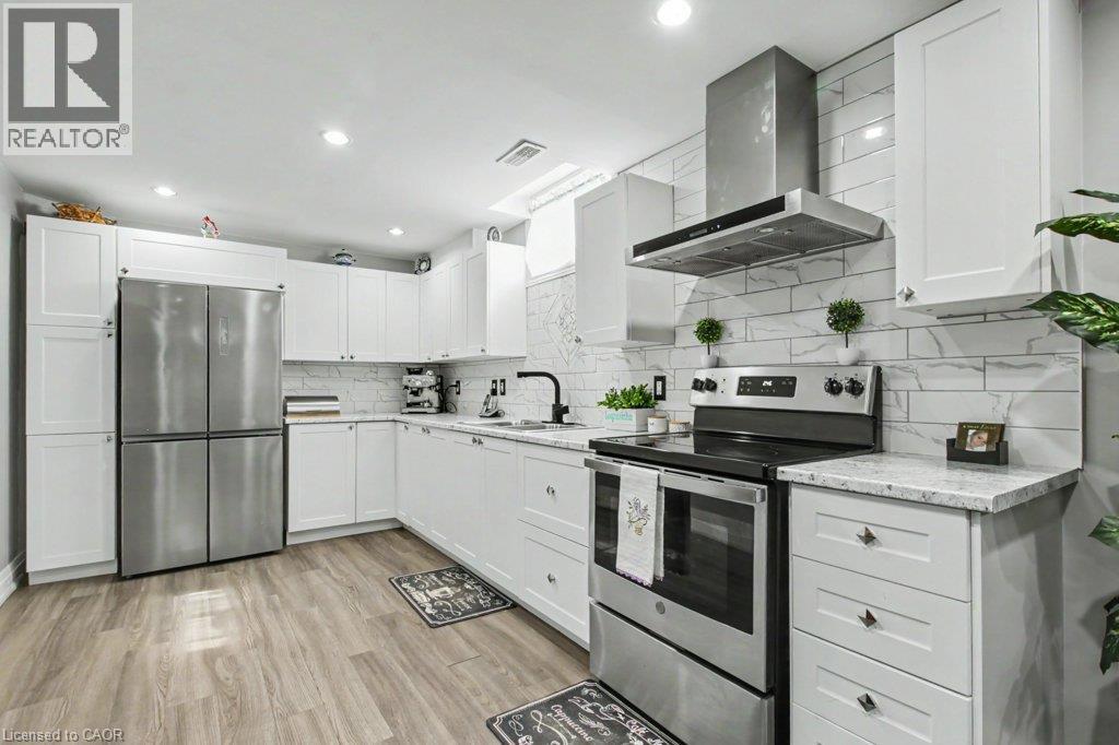 Contemporary kitchen featuring white shaker cabinetry, stainless steel appliances, light granite-finish countertops, subway tile backsplash, and wood-finish flooring - 284 Normanhurst Avenue, Hamilton, ON - Indoor Photo Showing Kitchen With Upgraded Kitchen