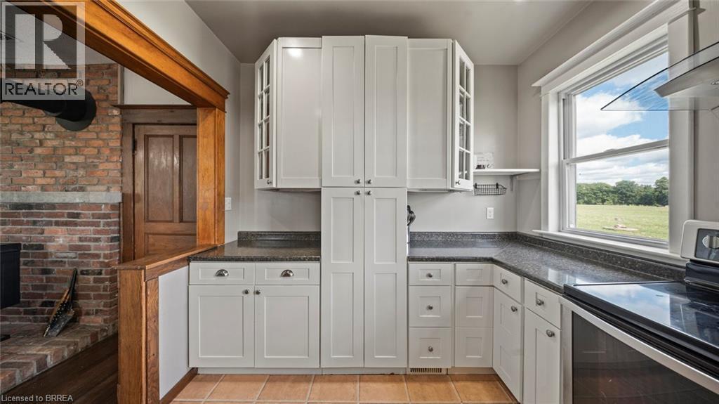 Kitchen featuring white shaker-style cabinetry, dark speckled countertops, and tile flooring - 3211 Highway 3, Jarvis, ON - Indoor Photo Showing Kitchen