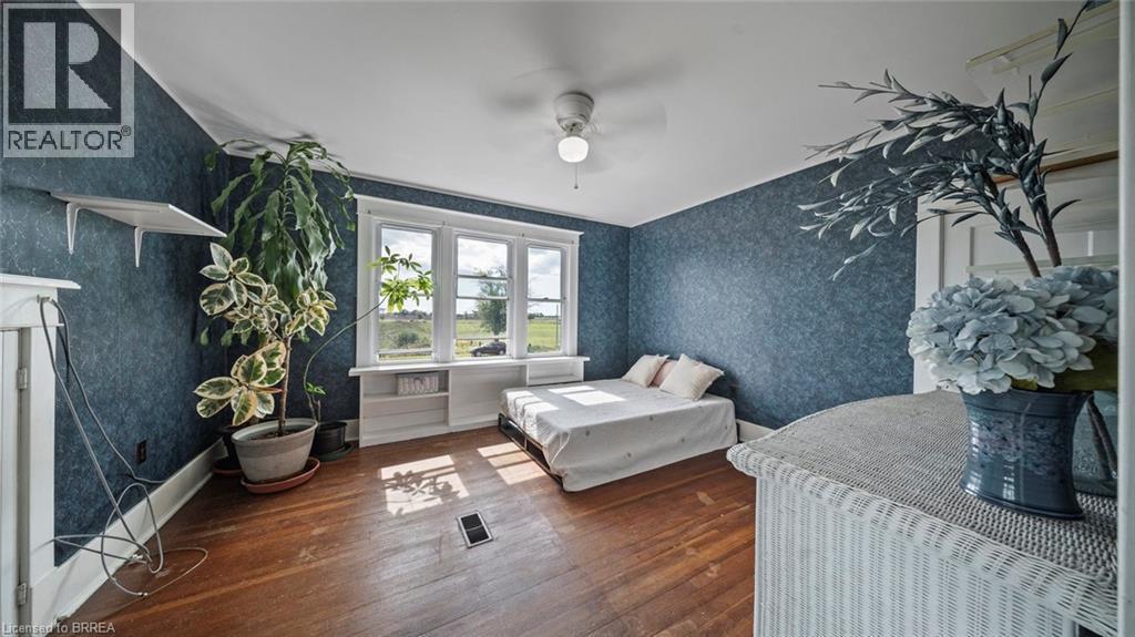 Inviting room with dark blue textured wallpaper and warm-toned wood-finish flooring - 3211 Highway 3, Jarvis, ON - Indoor