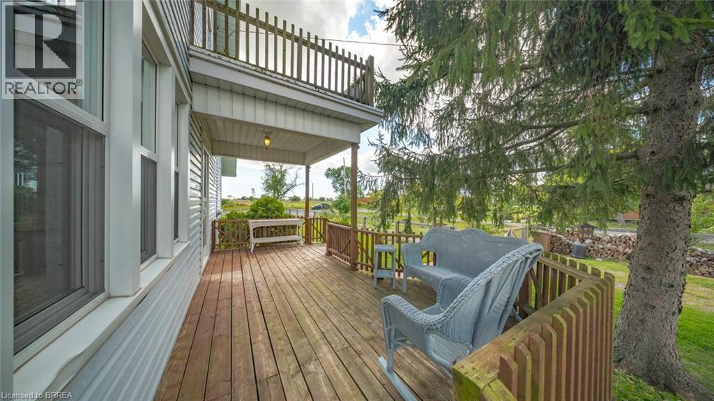 Expansive wood-finish deck with a wood railing and mature evergreen trees - 3211 Highway 3, Jarvis, ON - Outdoor With Deck Patio Veranda With Exterior