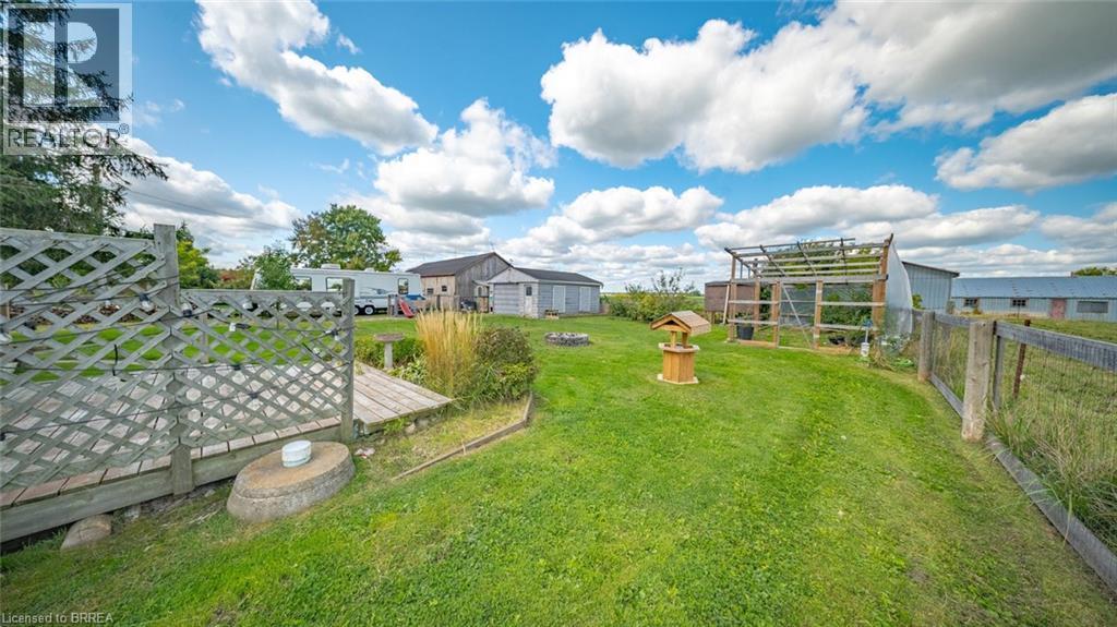 Expansive grassy area featuring multiple outbuildings, wood lattice fencing, and a wooden bridge structure - 3211 Highway 3, Jarvis, ON - Outdoor With View