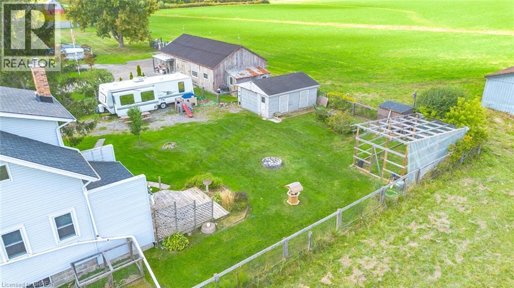 Expansive rear yard featuring a manicured lawn, multiple outbuildings, and a perimeter fence - 3211 Highway 3, Jarvis, ON - Outdoor