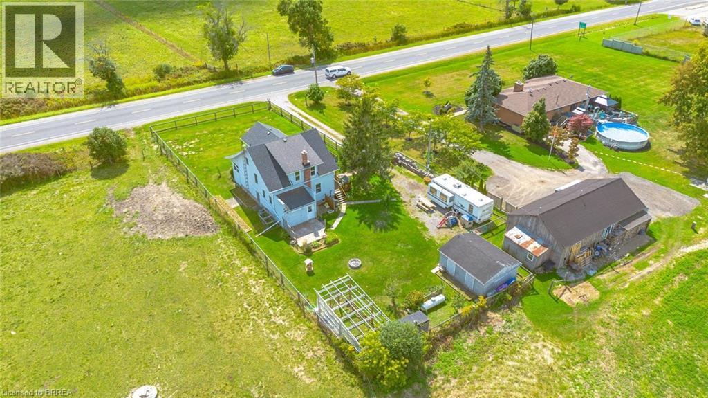 Expansive rural property featuring a light-colored main residence with a dark roof, a large separate barn structure, and an additional outbuilding - 3211 Highway 3, Jarvis, ON - Outdoor With View