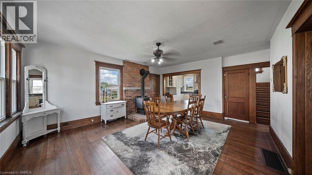 Spacious interior featuring wood-finish flooring, a brick accent wall with a wood-burning stove, multiple windows, and natural wood trim throughout - 3211 Highway 3, Jarvis, ON - Indoor Photo Showing Dining Room