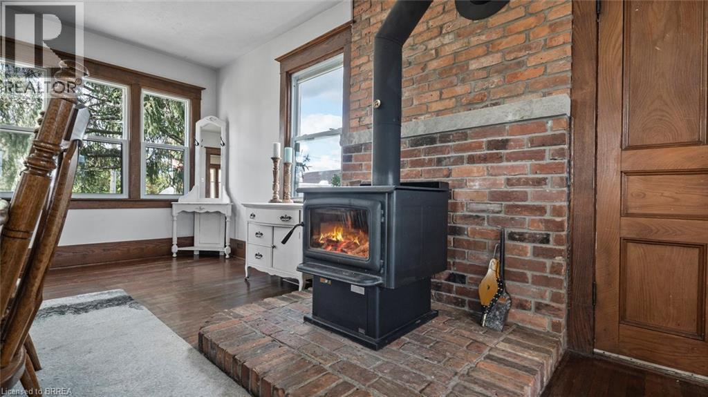 Wood-burning stove with a brick hearth and exposed brick wall - 3211 Highway 3, Jarvis, ON - Indoor Photo Showing Other Room With Fireplace