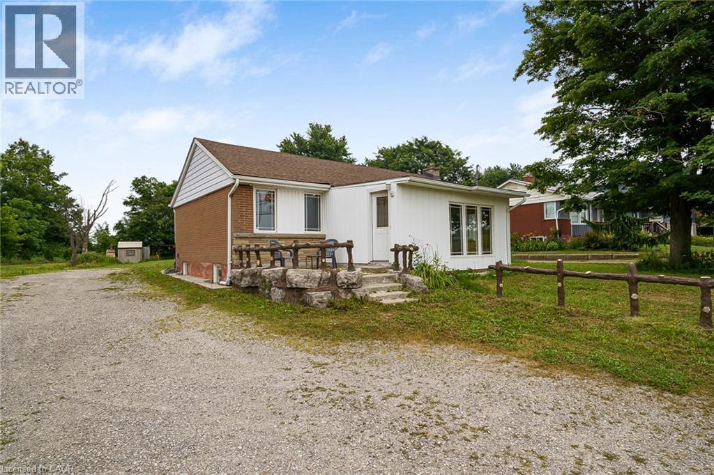 White and brick exterior featuring a brown shingle roof and a gravel driveway - 7332 Twenty Road E, Glanbrook, ON - Outdoor