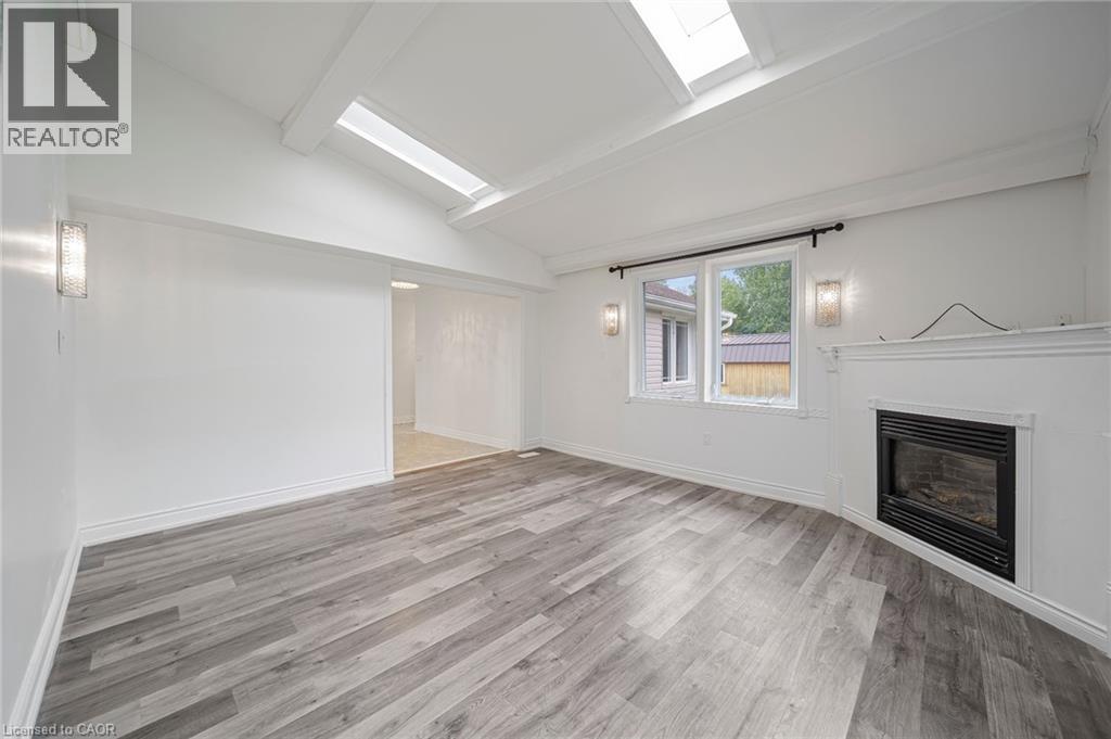 Vaulted ceilings with exposed beams and skylights complement the wood-finish flooring - 7332 Twenty Road E, Glanbrook, ON - Indoor With Fireplace