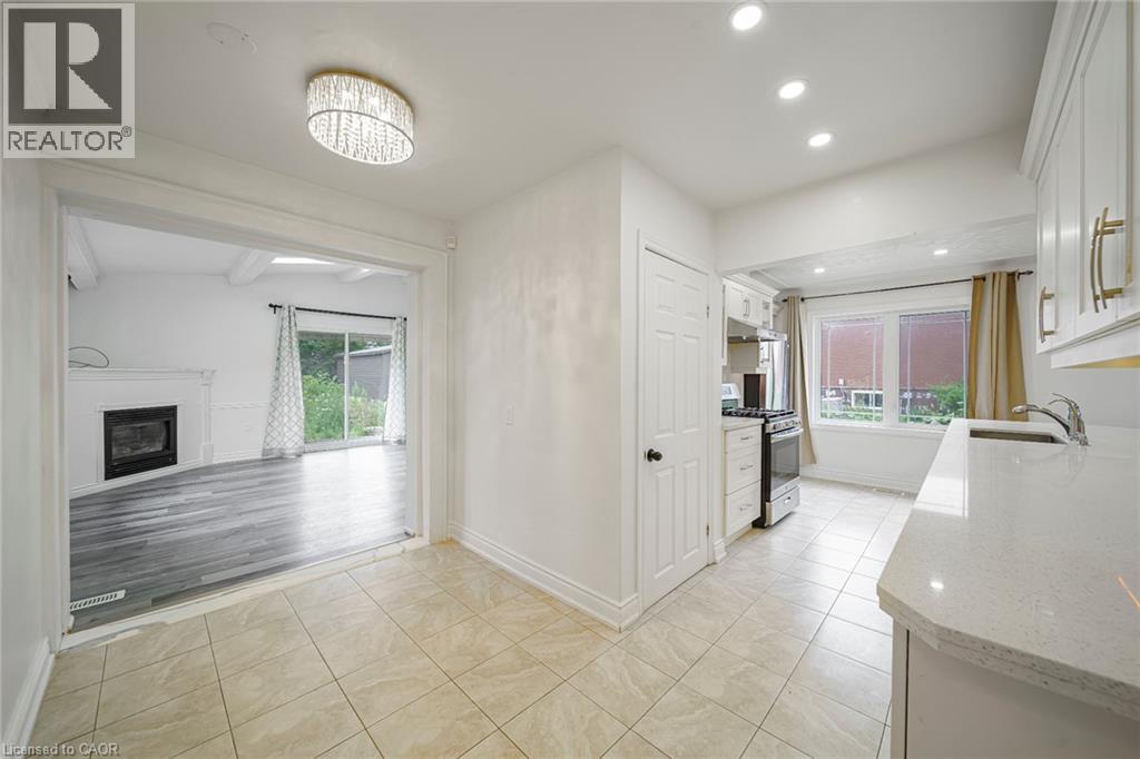Kitchen featuring tiled flooring, white cabinetry with gold-tone hardware, a stainless steel sink, and light-toned countertops - 7332 Twenty Road E, Glanbrook, ON - Indoor Photo Showing Other Room