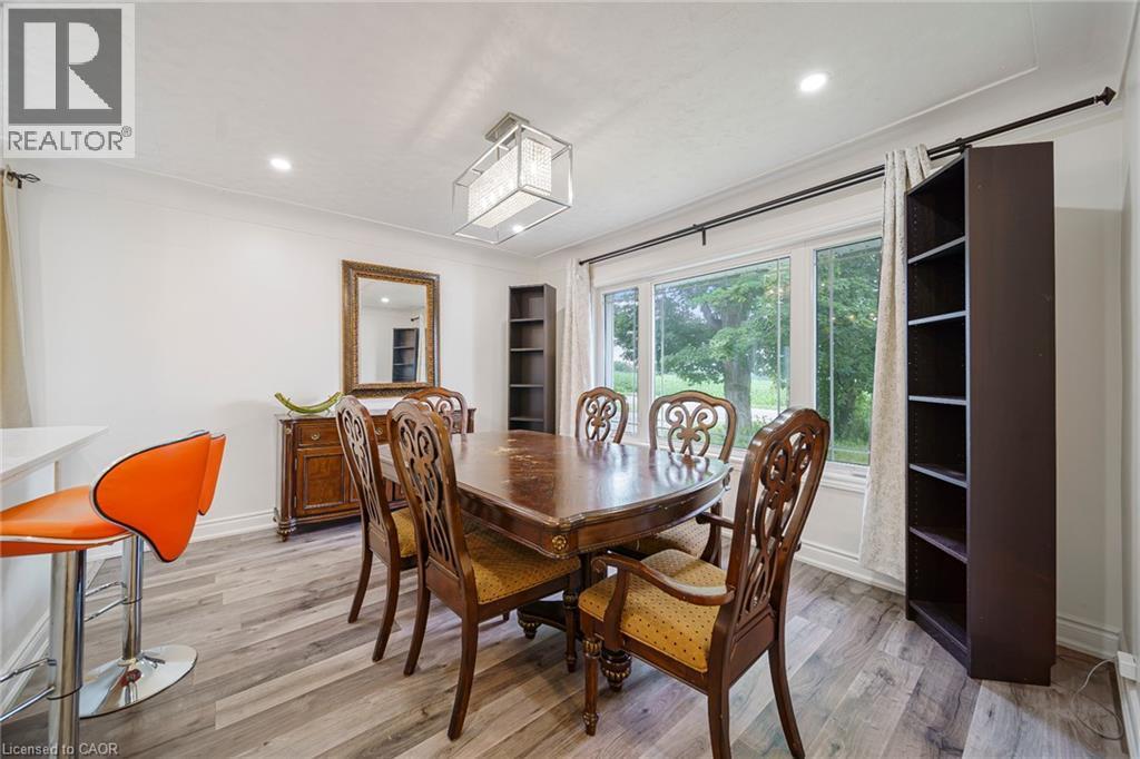 Bright dining area featuring wood-finish flooring, a contemporary chandelier, recessed lighting, and a large window offering natural illumination - 7332 Twenty Road E, Glanbrook, ON - Indoor Photo Showing Dining Room