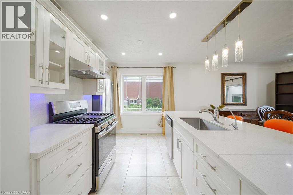 Contemporary kitchen featuring white cabinetry, stainless steel appliances, a center island with an undermount sink, and recessed lighting - 7332 Twenty Road E, Glanbrook, ON - Indoor Photo Showing Kitchen
