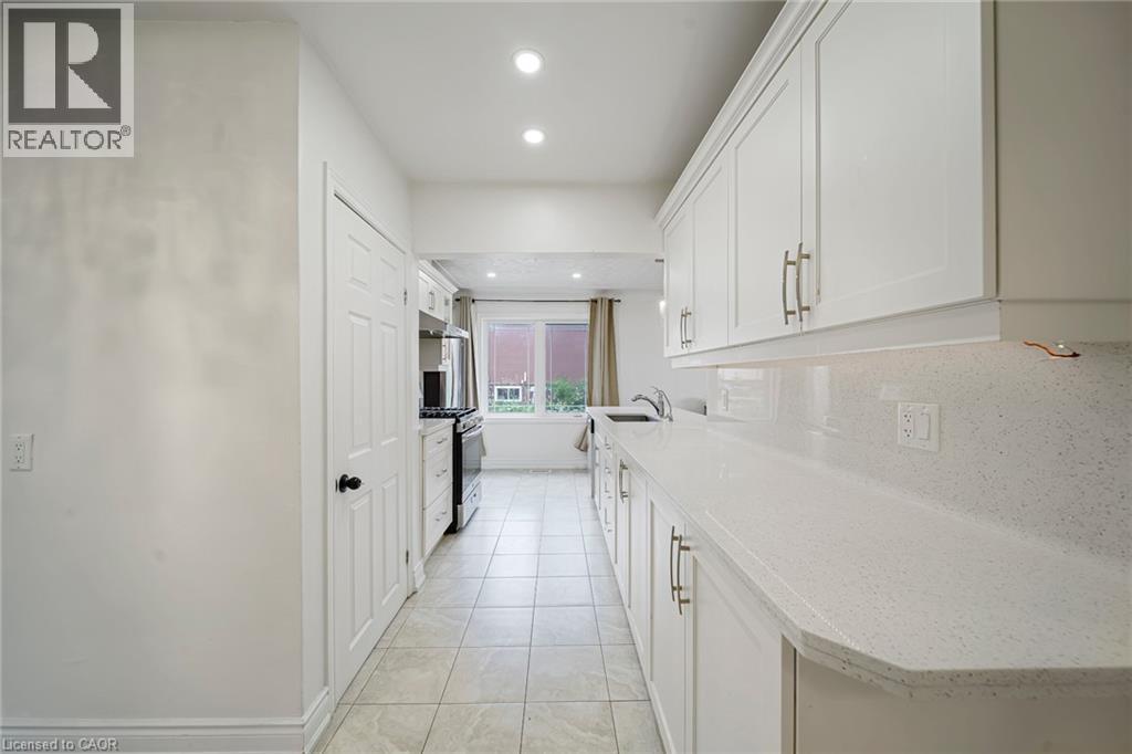 Galley kitchen featuring white cabinetry, light-toned countertops, tile flooring, and recessed lighting - 7332 Twenty Road E, Glanbrook, ON - Indoor Photo Showing Kitchen