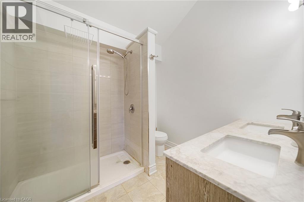 Dual vanity with undermount sinks and brushed nickel faucets, featuring a stone-finish countertop - 7332 Twenty Road E, Glanbrook, ON - Indoor Photo Showing Bathroom