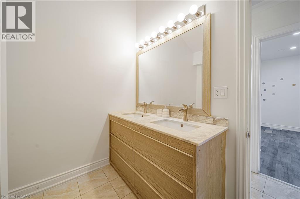 Dual vanity featuring a light wood-finish cabinet with six drawers, an integrated stone countertop, and two undermount sinks - 7332 Twenty Road E, Glanbrook, ON - Indoor Photo Showing Bathroom