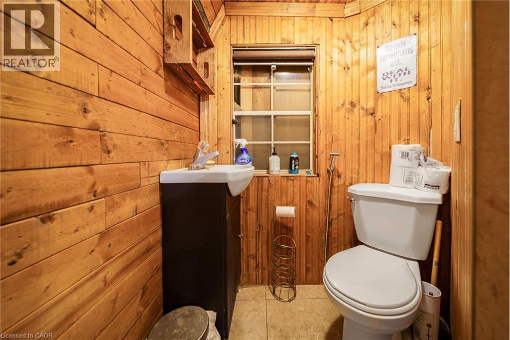 Bathroom featuring wood plank walls, a single window, and a white toilet - 7332 Twenty Road E, Glanbrook, ON - Indoor Photo Showing Bathroom