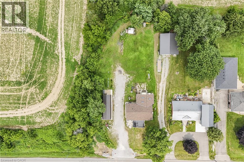 Aerial view showcasing a residential property with a brown-roofed home, a long gravel driveway, and a detached outbuilding - 7332 Twenty Road E, Glanbrook, ON - Outdoor With View