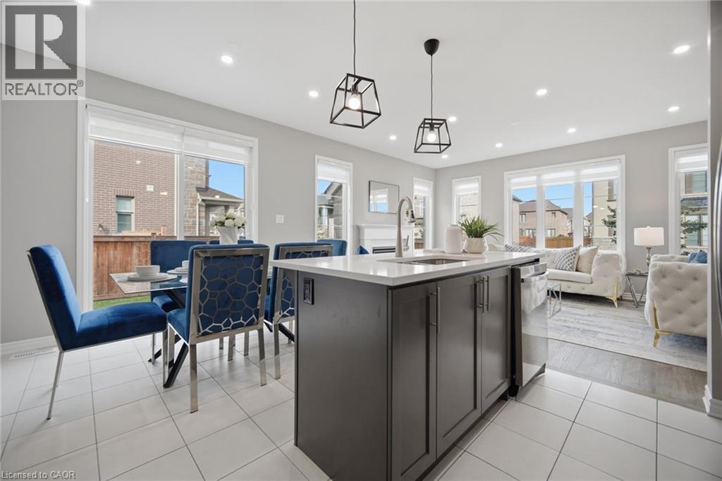 Modern kitchen island with a white countertop and a stainless steel sink, complemented by two black geometric pendant lights - 542 Boyd Lane, Milton, ON - Indoor