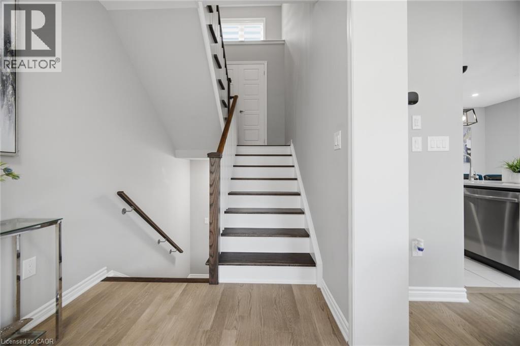 Staircase featuring wood-finish treads and risers, a wood newel post and handrail, and a white baseboard - 542 Boyd Lane, Milton, ON - Indoor Photo Showing Other Room
