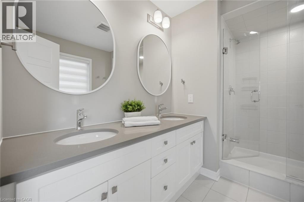 Double vanity with white cabinetry and integrated sinks, complemented by a glass-enclosed shower with subway tile surround, polished chrome fixtures, and neutral floor tiling - 542 Boyd Lane, Milton, ON - Indoor Photo Showing Bathroom