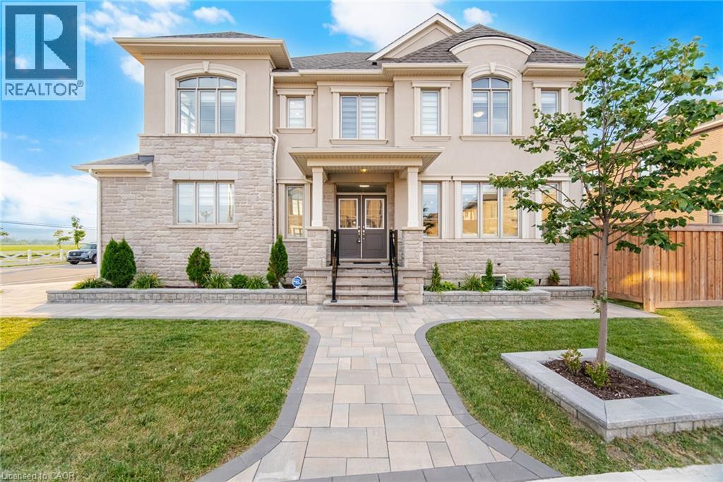 Stucco and stone facade home featuring a prominent arched window, paver walkway, and mature landscaping - 542 Boyd Lane, Milton, ON - Outdoor With Facade