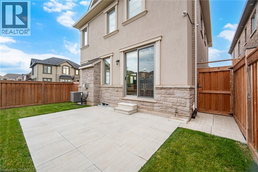 Private fenced backyard featuring a spacious patio, a well-maintained lawn, and a sliding glass door entry to the interior - 542 Boyd Lane, Milton, ON - Outdoor