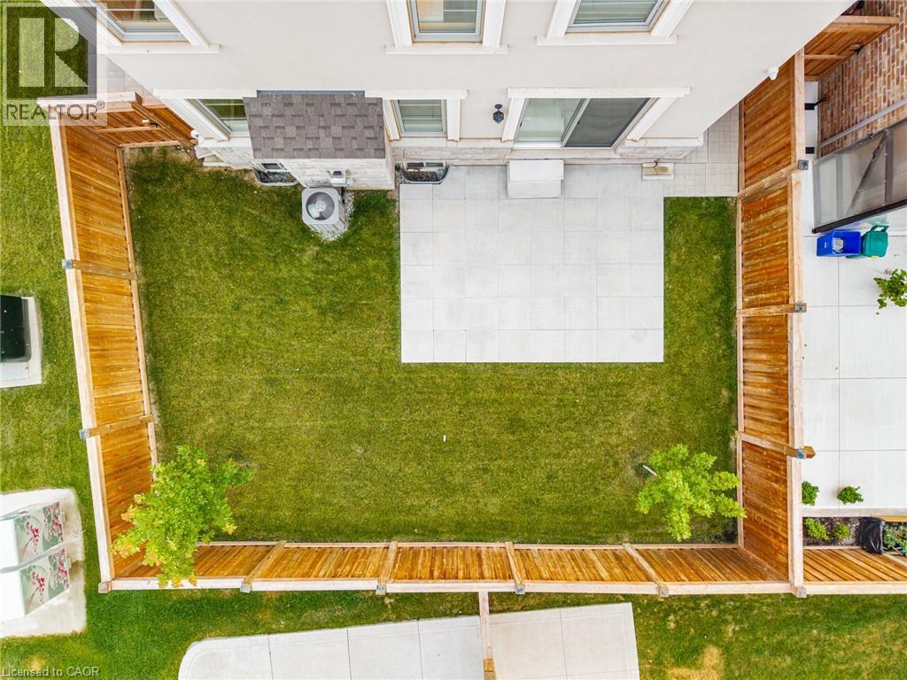 Enclosed backyard featuring a manicured lawn, a large patio space, and two mature trees - 542 Boyd Lane, Milton, ON - Outdoor