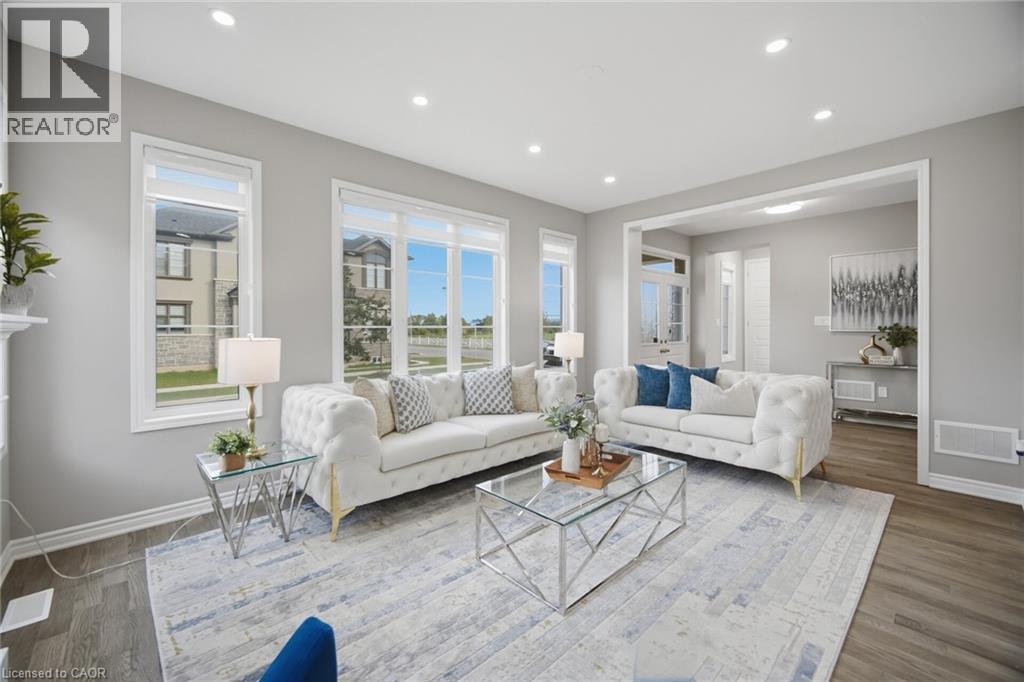 Spacious living area featuring large windows, recessed lighting, wide plank wood-finish flooring, and crisp white trim - 542 Boyd Lane, Milton, ON - Indoor Photo Showing Living Room