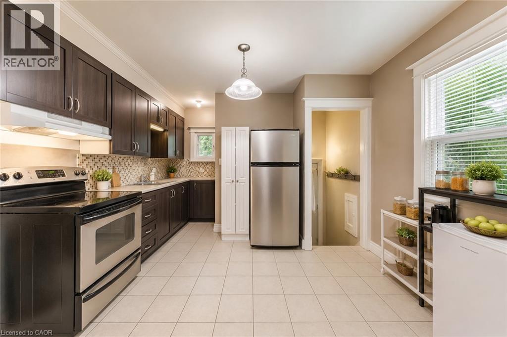 Kitchen featuring dark wood-finish cabinetry, stainless steel appliances, and light tile flooring - 74 Royal Avenue, Hamilton, ON - Indoor Photo Showing Kitchen