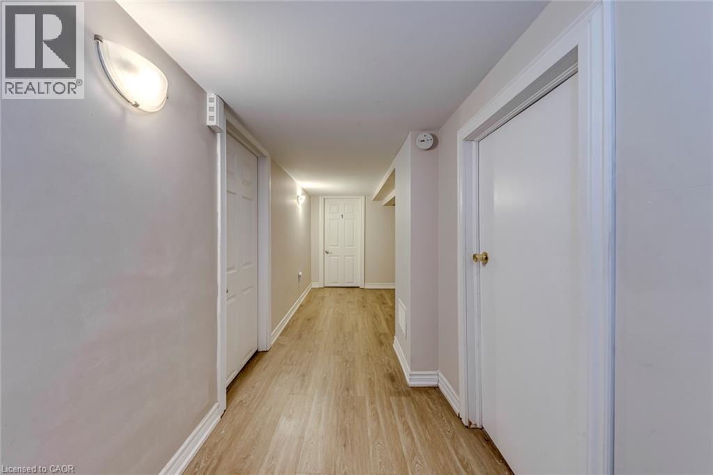 Hallway featuring wood-finish flooring, white doors, and contemporary wall sconces - 74 Royal Avenue, Hamilton, ON - Indoor Photo Showing Other Room