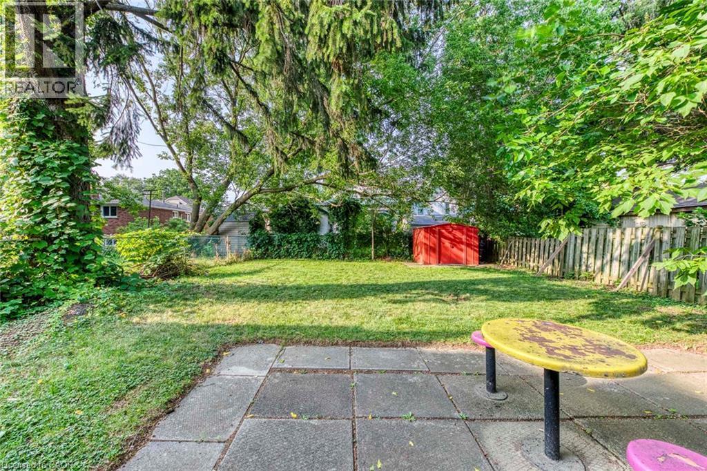 Spacious backyard featuring a stone paver patio, established trees, and a red shed - 74 Royal Avenue, Hamilton, ON - Outdoor
