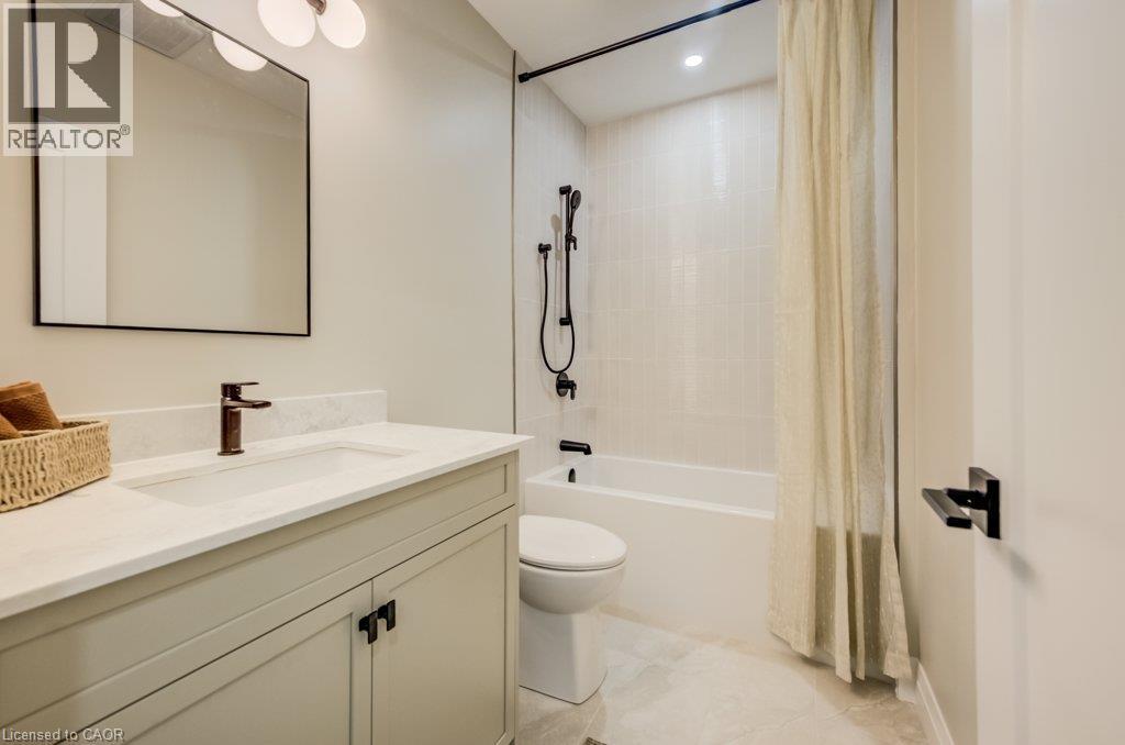 Modern bathroom featuring a light-toned vanity with a rectangular undermount sink, a dark bronze faucet, and a quartz countertop - 210 Heritage Drive Unit# Main, Kitchener, ON - Indoor Photo Showing Bathroom