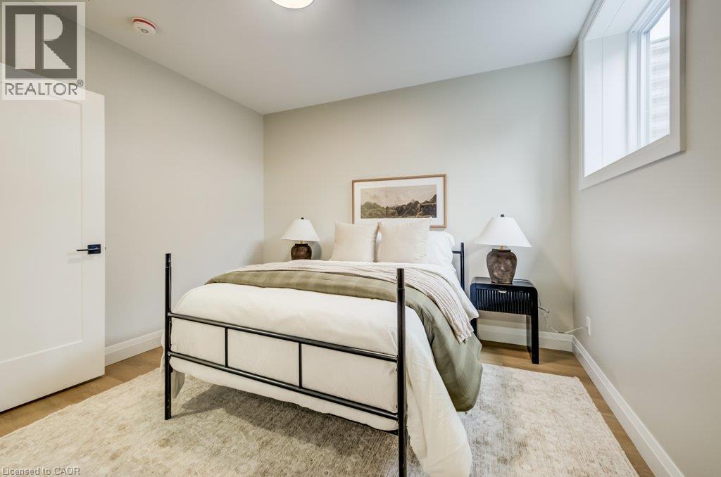 Bedroom featuring light wood-finish flooring, a white flat-panel door with black hardware, recessed ceiling lighting, and a horizontal window providing natural light - 210 Heritage Drive Unit# Main, Kitchener, ON - Indoor Photo Showing Bedroom