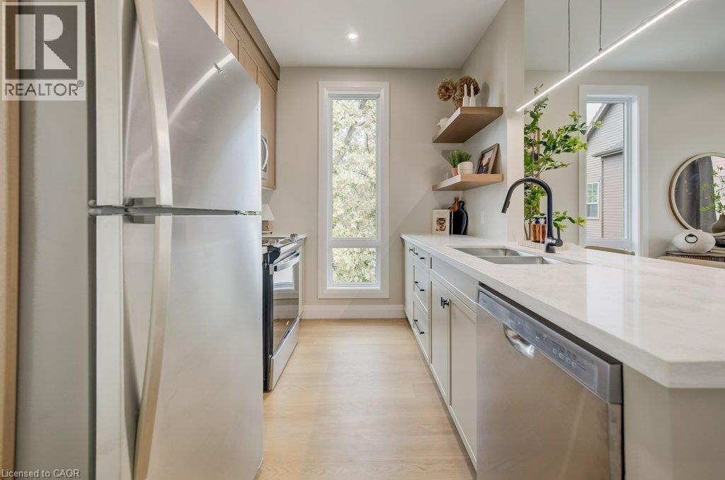 Modern kitchen featuring stainless steel appliances, light wood-finish flooring, white countertops, a black gooseneck faucet, and open wood shelving - 210 Heritage Drive Unit# Main, Kitchener, ON - Indoor Photo Showing Kitchen With Double Sink