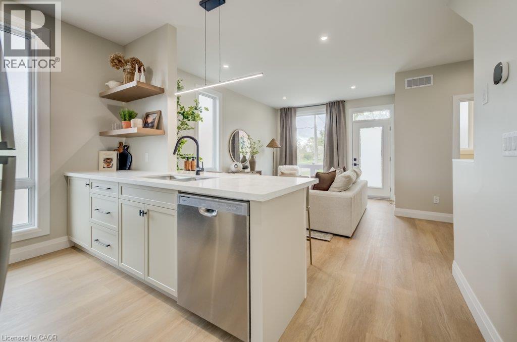 Kitchen island with white countertops, stainless steel dishwasher, and built-in sink with matte black faucet - 210 Heritage Drive Unit# Main, Kitchener, ON - Indoor Photo Showing Kitchen