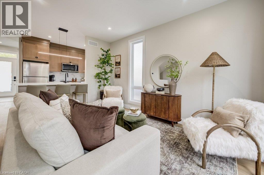 Open-concept living space featuring a modern kitchen with wood-finish cabinetry and stainless steel appliances - 210 Heritage Drive Unit# Main, Kitchener, ON - Indoor Photo Showing Living Room