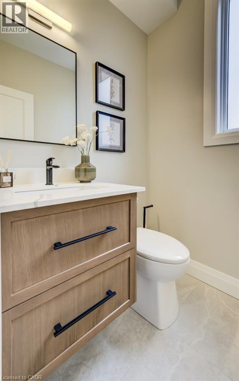 Vanity featuring wood-finish cabinetry, black hardware, and a white countertop with an integrated sink - 210 Heritage Drive Unit# Main, Kitchener, ON - Indoor Photo Showing Bathroom