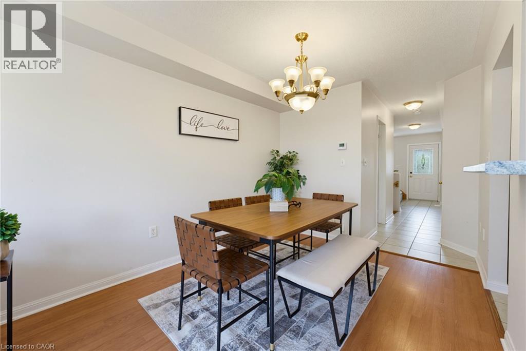 Dining area featuring wood-finish flooring, a brass chandelier, and light neutral wall colors - 4425 Peter Drive, Burlington, ON - Indoor Photo Showing Dining Room