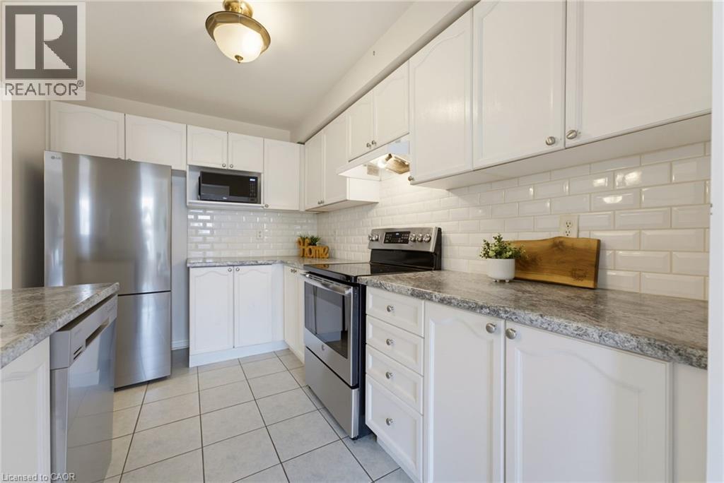 Kitchen featuring white cabinetry, gray speckled countertops, white subway tile backsplash, stainless steel appliances, and tile flooring - 4425 Peter Drive, Burlington, ON - Indoor Photo Showing Kitchen With Upgraded Kitchen