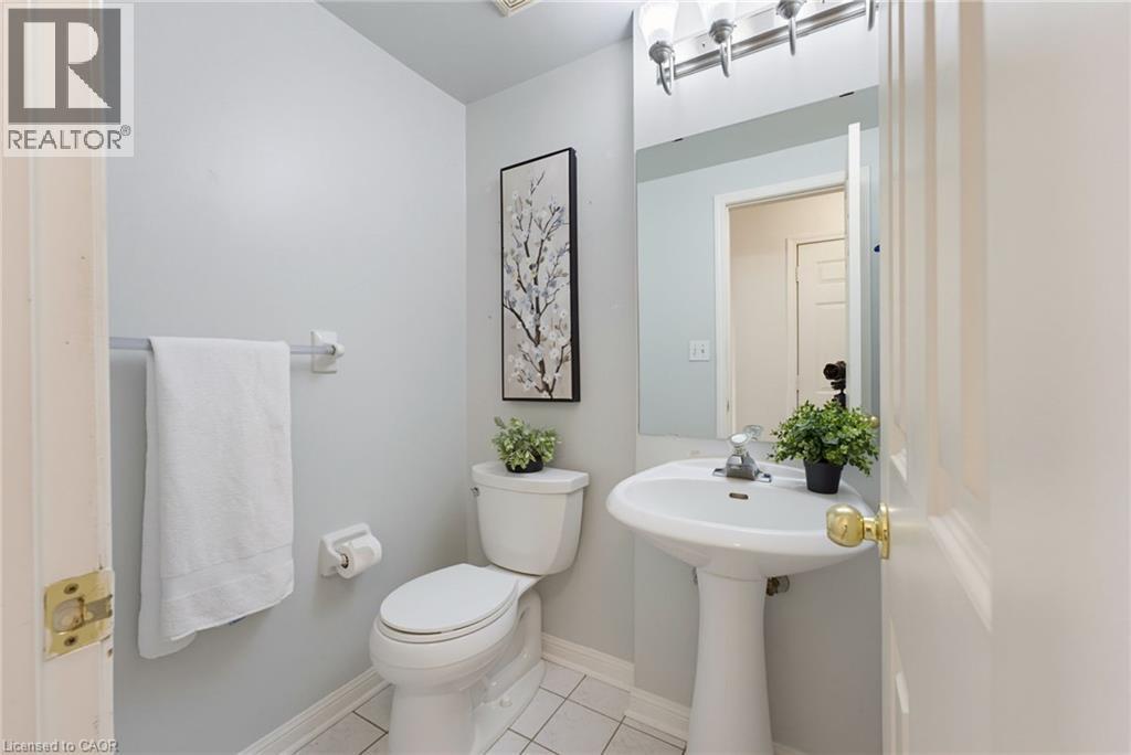 Pedestal sink with chrome faucet, white toilet, and tile flooring - 4425 Peter Drive, Burlington, ON - Indoor Photo Showing Bathroom