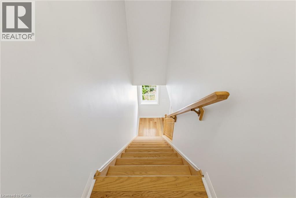 Hardwood staircase with natural wood treads and risers, complemented by a wooden handrail and balusters - 4425 Peter Drive, Burlington, ON - Indoor Photo Showing Other Room