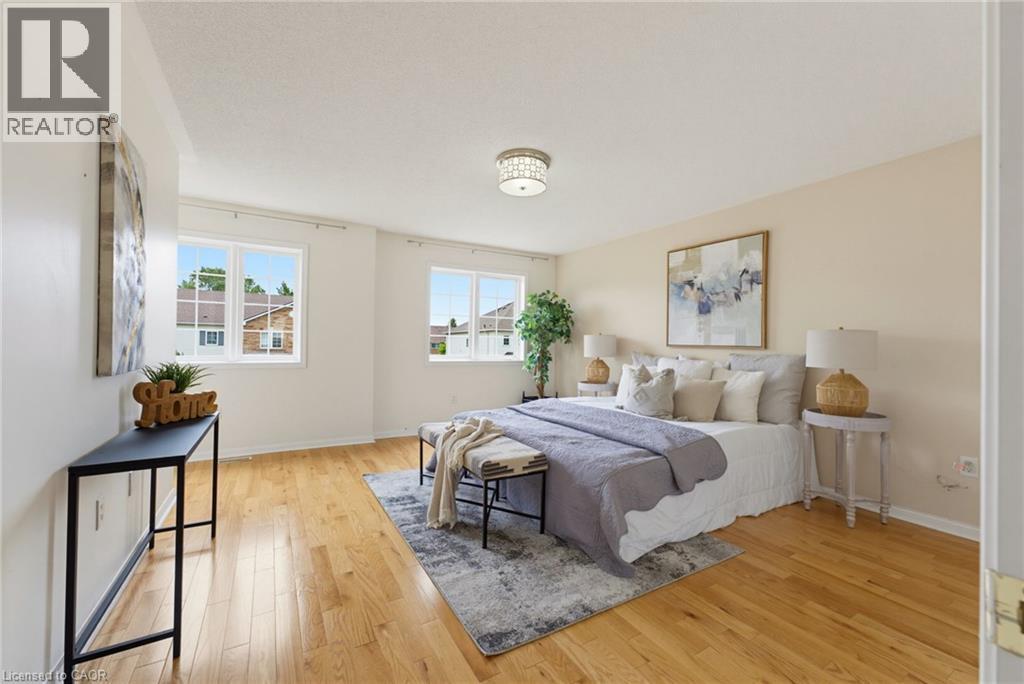 Hardwood-style flooring extends throughout this room, complemented by a contemporary flush-mount ceiling fixture and two large windows with white trim - 4425 Peter Drive, Burlington, ON - Indoor Photo Showing Bedroom