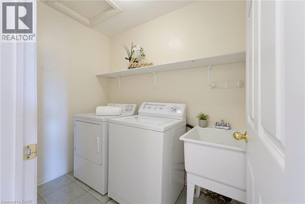 Dedicated laundry space featuring a utility sink, overhead shelving, and tile flooring - 4425 Peter Drive, Burlington, ON - Indoor Photo Showing Laundry Room