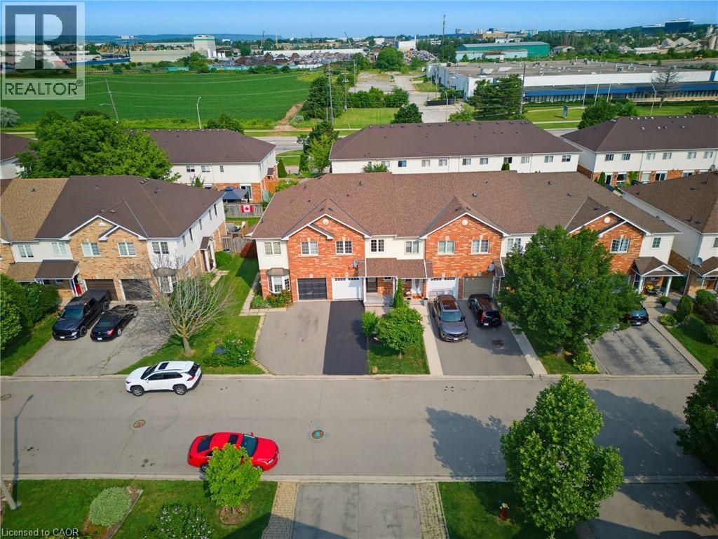Brick and siding townhome featuring a private driveway, single-car garage, and landscaped front yard - 4425 Peter Drive, Burlington, ON - Outdoor With View