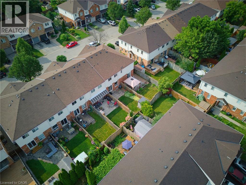 Aerial perspective highlighting a residential community with townhomes featuring brown shingle roofs, private fenced backyards, and paved patios - 4425 Peter Drive, Burlington, ON - Outdoor With View