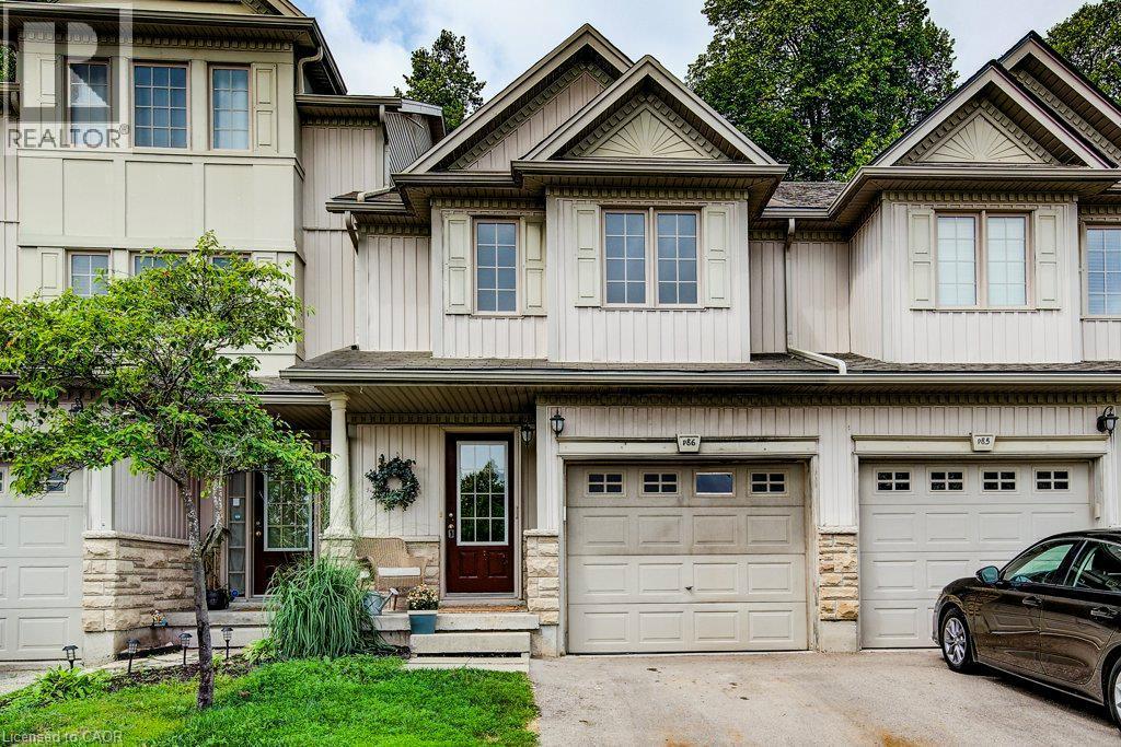 Multi-level townhouse exterior featuring vertical siding and stone veneer accents - 175 David Bergey Drive Unit# P86, Kitchener, ON - Outdoor With Facade