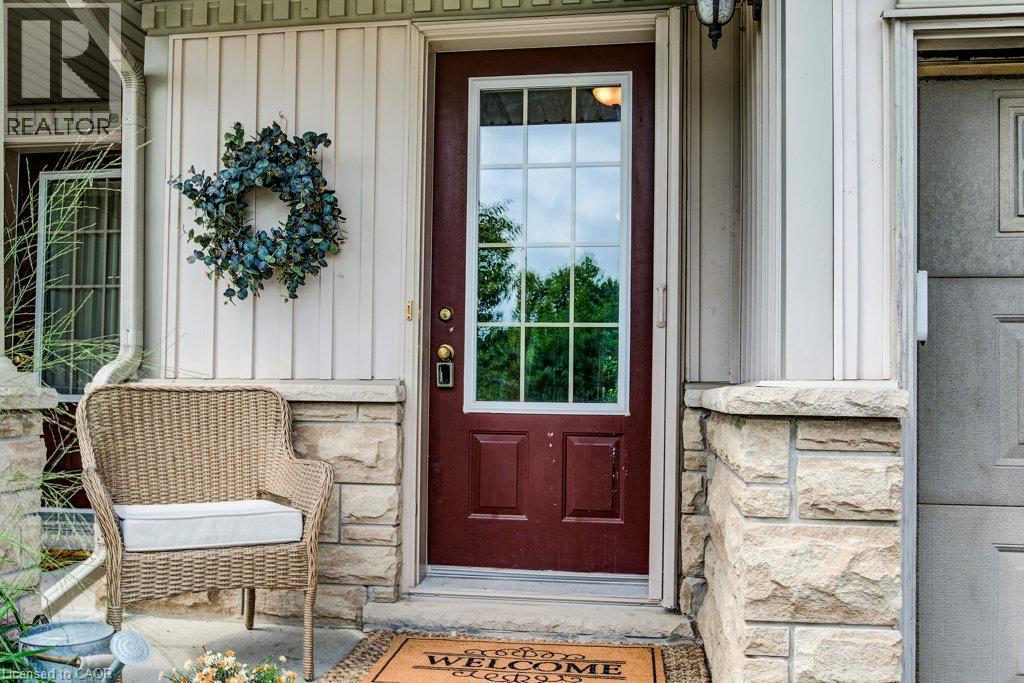 Entryway featuring a maroon paneled door with glass inserts, stone façade accents, vertical siding, and an overhead light fixture - 175 David Bergey Drive Unit# P86, Kitchener, ON - Outdoor With Exterior