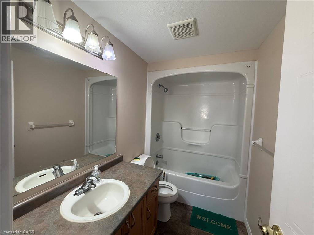 Bathroom featuring a single vanity with an oval sink, laminate countertop, and wood-finish cabinetry - 11 Hackberry Street Unit# 1, Kitchener, ON - Indoor Photo Showing Bathroom