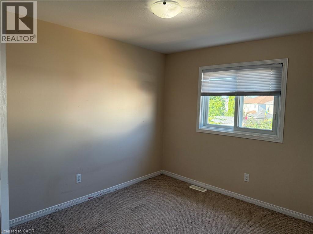 Neutral tone walls with an expansive window featuring horizontal blinds - 11 Hackberry Street Unit# 1, Kitchener, ON - Indoor Photo Showing Other Room